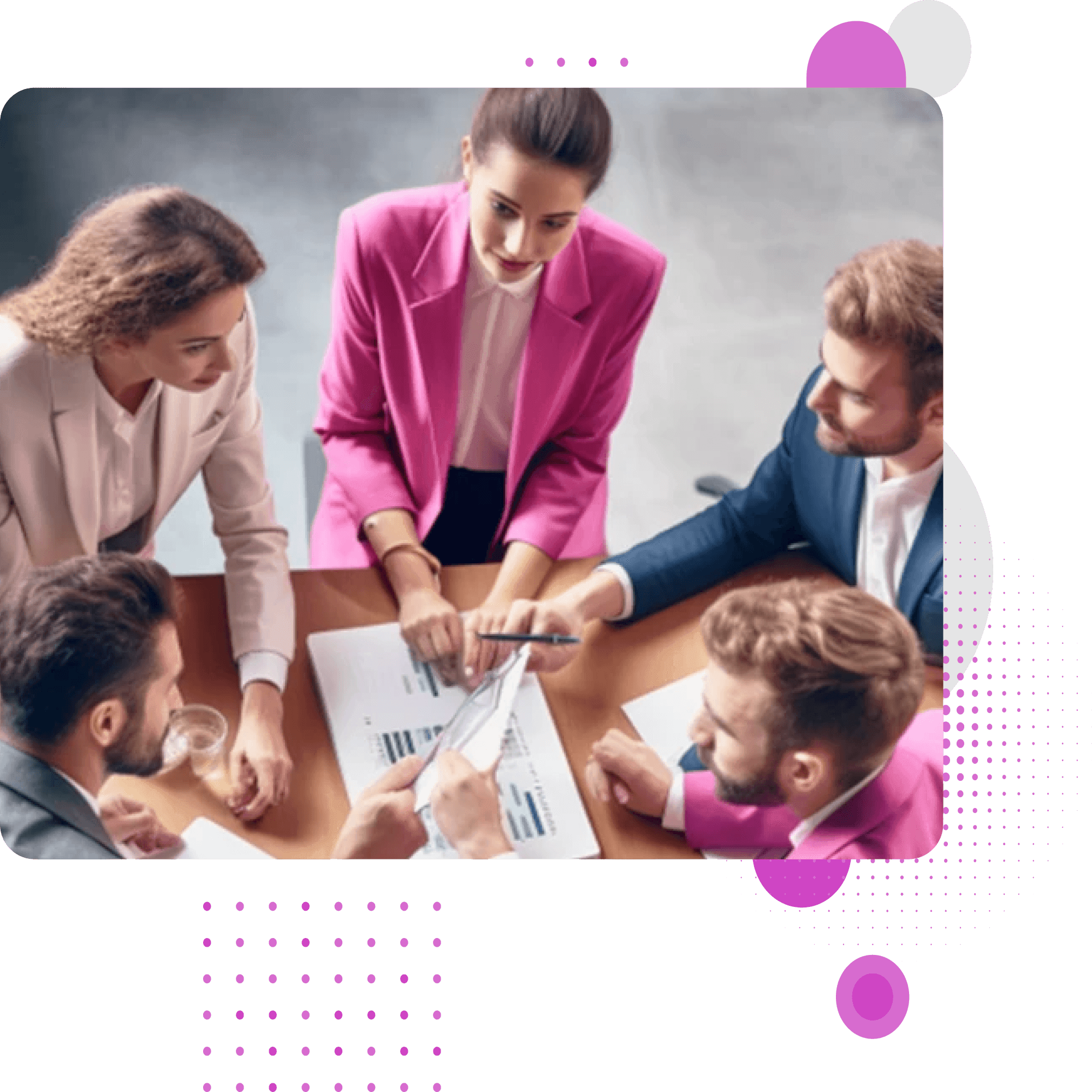 Five colleagues in pink and navy suits leaning over charts on a meeting table, seen from above