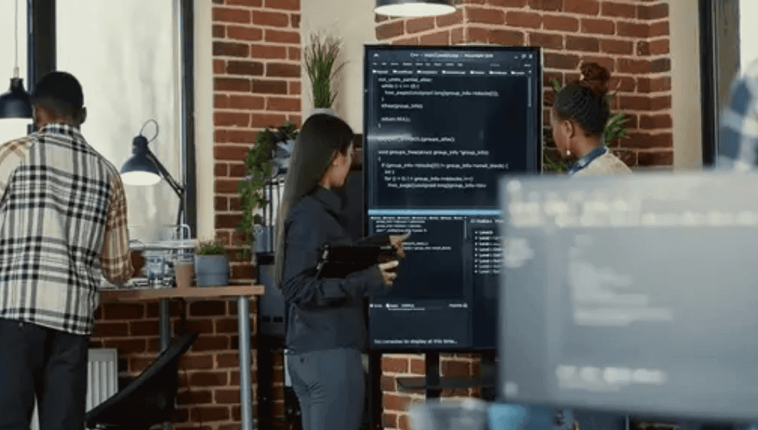 Developers in an office in front of a large screen of code