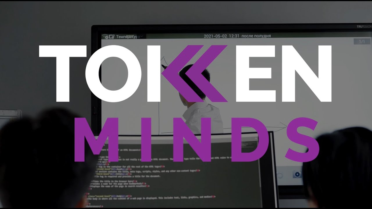 The TokenMinds logo over a classroom where a teacher writes on a screen above a monitor of code